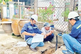 Workers from the Can Gio Clean Water Supply Company install smart water meters in Tam Thon Hiep commune, Can Gio district. (Photo: nhandan.vn) 