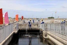 Workers spray water to clean the filtration tank and remove debris at the Binh Hung wastewater treatment plant in HCM City. (Photo: VNA)