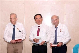 Nguyen Van Nen, Politburo member and Secretary of the Ho Chi Minh City Party Committee, presents the HCM City Badge to Olivier Parriaux and Bernard Bachelard at the meeting. (Photo: VNA)