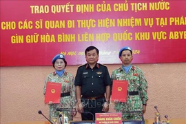 Deputy Minister of National Defence Senior Lieutenant General Hoang Xuan Chien (right) hands over the President's decision to two officers (Photo: VNA)