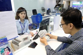 A customer conducts a foreign currency transaction at a banking office (Photo: VNA)