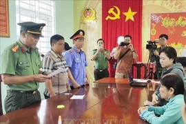 Tran Thi Hong Duyen and Bui Thi Anh Ngoc listen to their arrest warrant at the police station. (Photo: VNA)