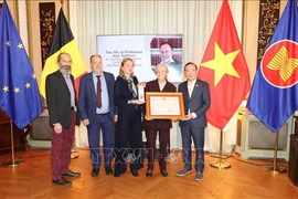 Vietnamese Ambassador to Belgium Nguyen Van Thao (R) presents the Friendship Order of the Vietnamese State in recognition of Jean Salmon's great contributions to the Vietnam-Belgium cooperation to his family. (Photo: VNA)