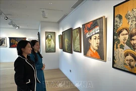 A staff of Thang Long Art Gallery staff introduces artworks to a visitor at the exhibition. (Photo: VNA)