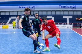 A Vietnamese futsal player (red) faces two Australian players at the semi-final match of the ASEAN Futsal Championship 2024 on November 8. (Photo: VNA)