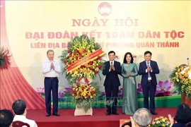 Party General Secretary To Lam (L) presents flowers to congratulate the Party Committee, People's Committee and Vietnam Fatherland Front Committee of Quan Thanh ward in Ba Dinh district of Hanoi. (Photo: VNA)