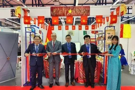 Ambassador Tran Quoc Khanh (middle) and trade counselor Hoang Duc Nhuan (left) cut the ribbon to launch the Vietnam pavilion at the fair. (Photo: VNA)