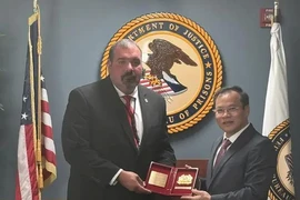 越南公安部副部长阮文龙中将向美国监狱管理局副局长夏恩·塞勒姆赠送纪念品。图自越通社