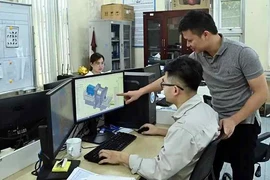 Les ingénieurs de la société Tomeco, à Hanoï, discutent de la conception de modèles de ventilateurs industriels. Photo : NHANDAN