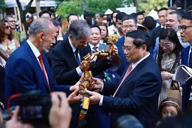 El primer ministro Pham Minh Chinh obsequia marionetas de agua a los delegados. (Foto: VNA)