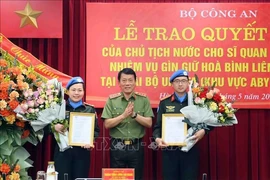 Заместитель министра общественной безопасности генерал-полковник Лыонг Там Куанг (в центре) вручает решения президента государства двум офицерам 29 мая. (Фото: ВИA)