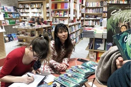 Hai Anh (droite) et Pauline Guitton dédicacent leur ouvrage à des lecteurs en France. Photo: tuoitre.vn