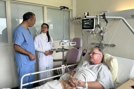 Jacques Ballout, chef du service de cardiologie de l’hôpital Pierre-Bérégovoy, et une stagiaire vietnamienne au chevet d’un patient français. Photo : VNA