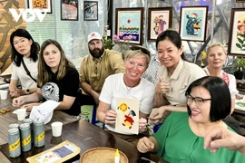 En visitant l'atelier Vun Art, les touristes étrangers peuvent expérimenter la réalisation de peintures sur tissus avec l’aide des artisans handicapés de l’atelier. Photo: VOV