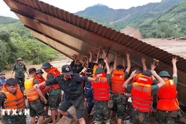 Des secouristes recherchent des personnes dans des maisons effondrées à la suite d’un glissement de terrain causé par de fortes pluies. Photo: VNA