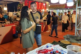 Maria et son petit ami cherchent des plats vietnamiens lors du festival le soir du 23 octobre. Photo: CPV