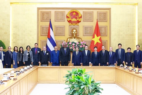 PM Pham Minh Chinh (8th from right), President of the National Assembly of People's Power of Cuba Esteban Lazo Hernandez (9th from right), and officials of the two countries pose for a group photo at the meeting in Hanoi on July 24. (Photo: VNA)