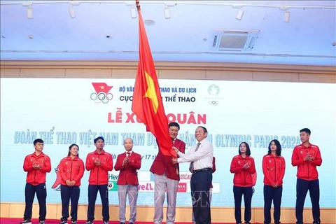 Le ministre de la Culture, des Sports et du Tourisme, Nguyen Van Hung (droite), remet le drapeau symbolisant la détermination à concourir au chef de la délégation vietnamienne aux JO de Paris 2024, Dang Ha Viet. Photo: VNA