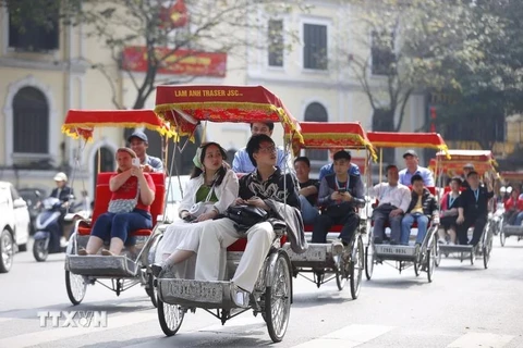 游客坐三轮车参观河内旅游景点。图自越通社