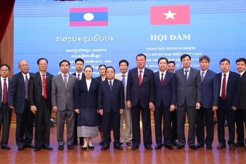 L'inspecteur général du gouvernement vietnamien Doan Hong Phong et son homologue lao Khamphan Phommaphat prennent une photo avec les inspecteurs de deux pays. Photo: VNA