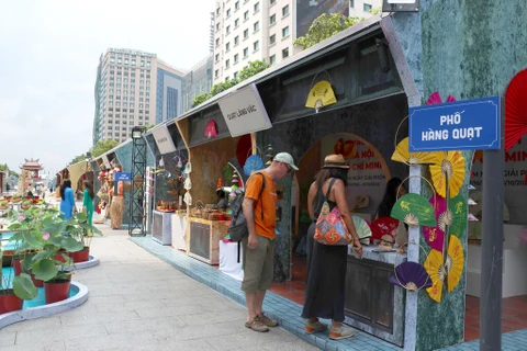 Les touristes étrangers visitent un stand des produits de Hanoï. Photo : Quang Châu/CVN