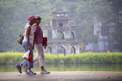 Les touristes étrangers se promènent au bord du lac Hoan Kiem. Photo : VNA