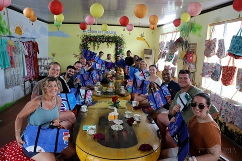 Los turistas extranjeros utilizan la bolsa hecha de lona plástica de la Cooperativa Green Life Ha Long. (Foto: VNA)