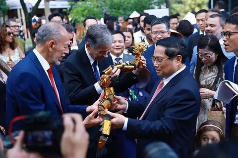 Le Premier ministre Pham Minh Chinh offre des marionnettes sur l'eau à des délégués. Photo : VNA