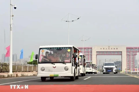 Electric cars carrying tourists passing Bac Luan II bridge (Photo: VNA)