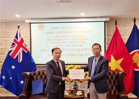 Ambassador Pham Hung Tam (R) hands over 12,700 AUD (8,700 USD) to the delegation to help victims of Typhoon Yagi (Photo: VNA)