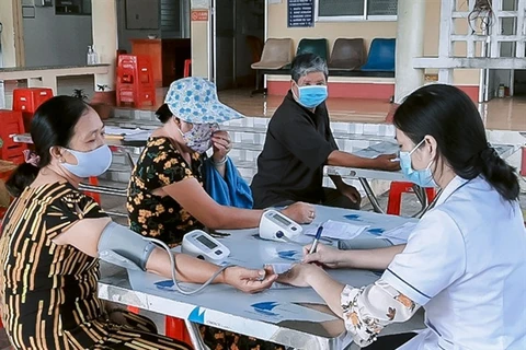 Medical staff member checks blood pressure for people in Long An province. (Photo: baolongan.vn)