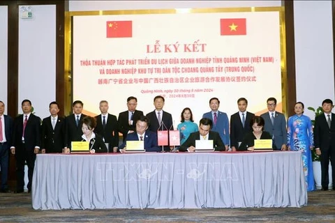 Representatives from Quang Ninh and Guangxi Zhuang Autonomous Region witness the signing of a tourism development cooperation agreement between the two localities' enterprises. (Photo: VNA)