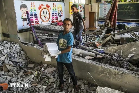 Niños junto a las ruinas de una escuela afectada por un ataque aéreo israelí en la ciudad de Gaza el 25 de junio. (Foto: Xinhua/VNA)