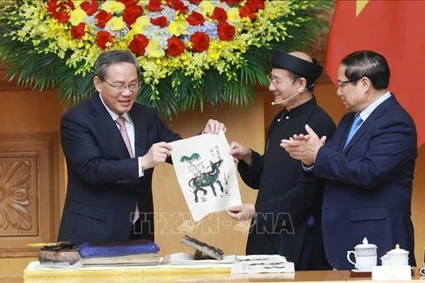 El primer ministro vietnamita, Pham Minh Chinh (derecha), y su par chino, Li Qiang, experimentaron de primera mano la creación de una pintura popular de la etnia Dong Ho. (Foto: VNA)