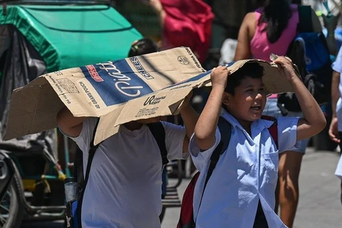 Students use a cardboard to protect themselves from the sun during a hot day in Manila on April 2, 2024. (Photo: philstar.com) 