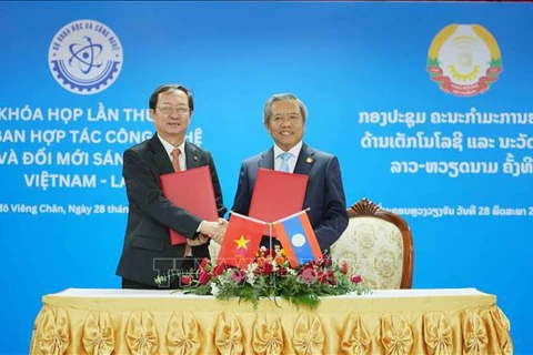 Vietnamese Minister of Science and Technology Huynh Thanh Dat (L) and Lao Minister of Technology and Communications Boviengkham Vongdara exchange the minutes of the first session of the Vietnam-Laos Committee for Cooperation in Technology and Innovation in Vientiane, Laos, on May 28. (Photo: VNA)