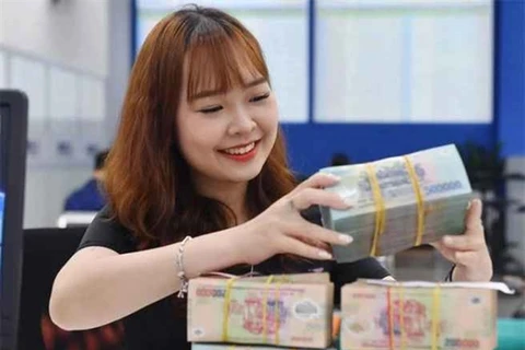 A bank teller counts money at a transaction office in Hanoi. (Photo: cafef.vn)