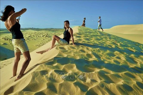 Foreign tourists at Bau Trang sand dune in the south central province of Binh Thuan. Vietnam expects to serve 17-18 million international tourists and 110 million domestic holidaymakers, and pocket some 840 trillion VND from the industry this year. (Photo: VNA)