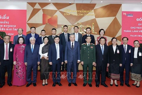 President To Lam (middle, first row) takes a group photo with representatives of Star Telecom (Unitel) as part of his state visit to Laos on July 11. (Photo: VNA)