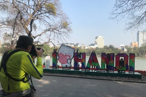 Foreign tourists take photos at Hoan Kiem Lake (Photo: daidoanket.vn)