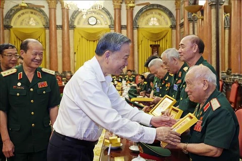 President To Lam presents a photo of President Ho Chi Minh to 96-year-old Major General Vo So, head of the liaison board of veterans of the Parachute-Commando Division 305 (Photo: VNA)