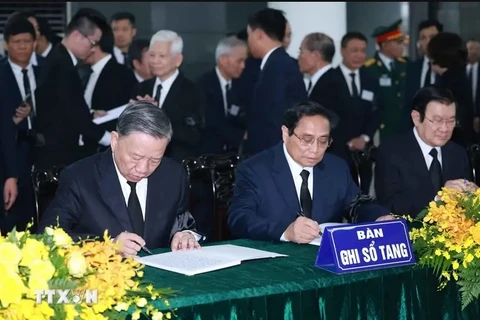 Politburo member and State President To Lam (left), and Politburo member and Prime Minister Pham Minh Chinh (centre) write in the book of condolences. (Photo: VNA)