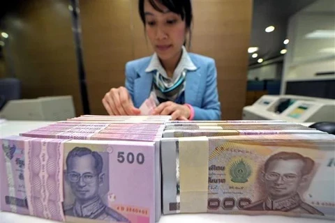 A bank employee counts Thai baht notes in Bangkok, Thailand (Photo: AFP/VNA)