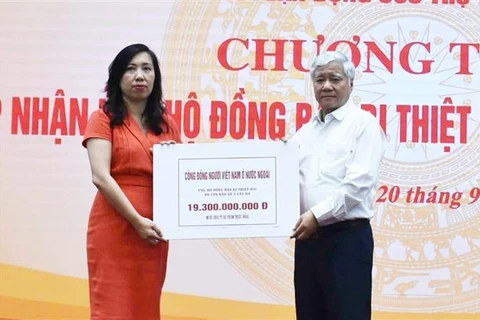 President of the Vietnam Fatherland Central Committee Do Van Chien (R) receives token of fund raised among OVs abroad for storm-hit people from Deputy Foreign Minister and Chairwoman of the State Committee for OV Affairs Le Thi Thu Hang. (Photo: VNA)