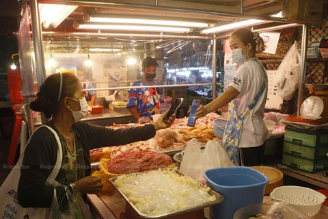 A shopper uses a QR code to make contactless payment to her butcher in Nonthaburi. (Photo: Bangkokpost)