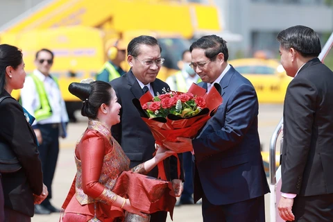 Prime Minister Pham Minh Chinh and his encourage are greeted at the airport by Lao Minister of Energy and Mines Phosay Sayyasone and other Lao officials, along with Vietnamese Ambassador to Laos Nguyen Minh Tam, among other diplomats. (Photo: VNA)