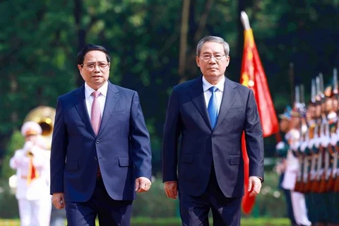 Prime Minister Pham Minh Chinh and Chinese Premier Li Qiang (R) review the guard of honour of the People's Army of Vietnam. (Photo: VNA)