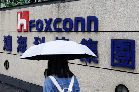 A woman carrying an umbrella walks past the logo of Foxconn outside a company's building in Taipei, Taiwan, Oct. 31, 2022. (Photo: Reuters)