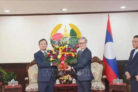 Ambassador Nguyen Minh Tam (left) present flowers to congratulate Lao Foreign Minister Thongsavanh Phomvihane on the 49th anniversary of Laos' National Day. (Photo: VNA) 