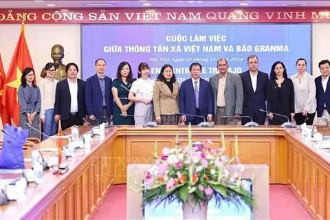 VNA Deputy General Director Nguyen Tuan Hung (sixth from right), Granma newspaper's Deputy Editor-in-Chief Oscar Alberto Sanchez Serra (fifth from right) and other delegates take a group photo at the meeting in Hanoi on December 3. (Photo: VNA)